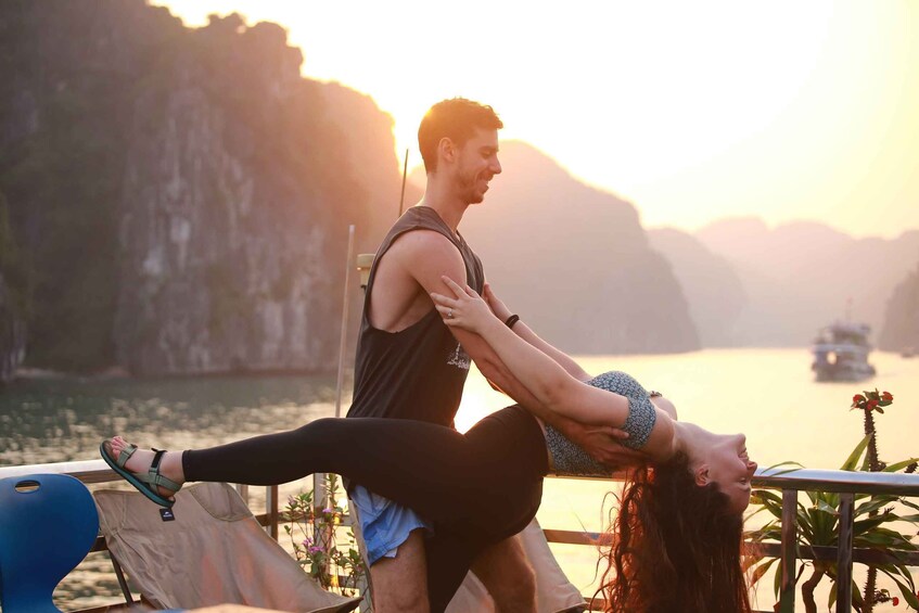 A person performing a yoga pose on a balcony overlooking a body of water with cliffs in the background. 1