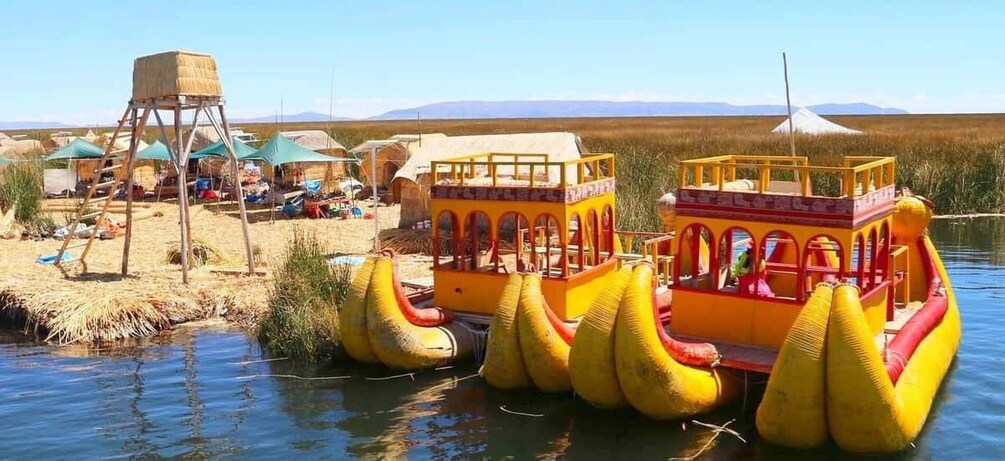 A yellow boat with a red canopy, floating on water with a thatched structure nearby. 5
