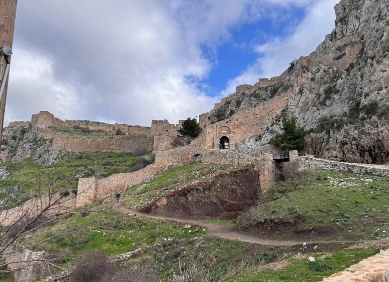 A historic stone fortification with a gate, set against a mountainous backdrop. 3