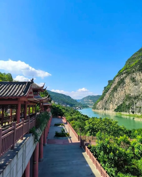 A traditional Chinese pavilion overlooking a river with a mountainous backdrop. 3