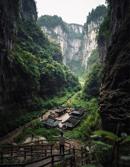 A traditional building nestled in a lush valley between steep cliffs. 1