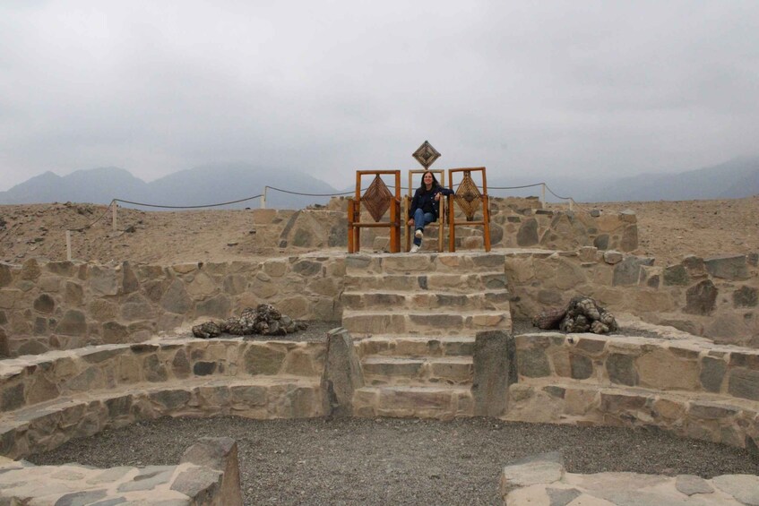 A stone structure with a person sitting on a wooden bench. 3