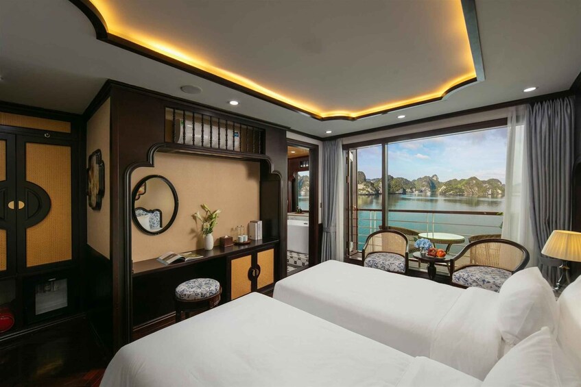 A hotel room with two beds, a desk, a large window with a view of a body of water, and a balcony. 2