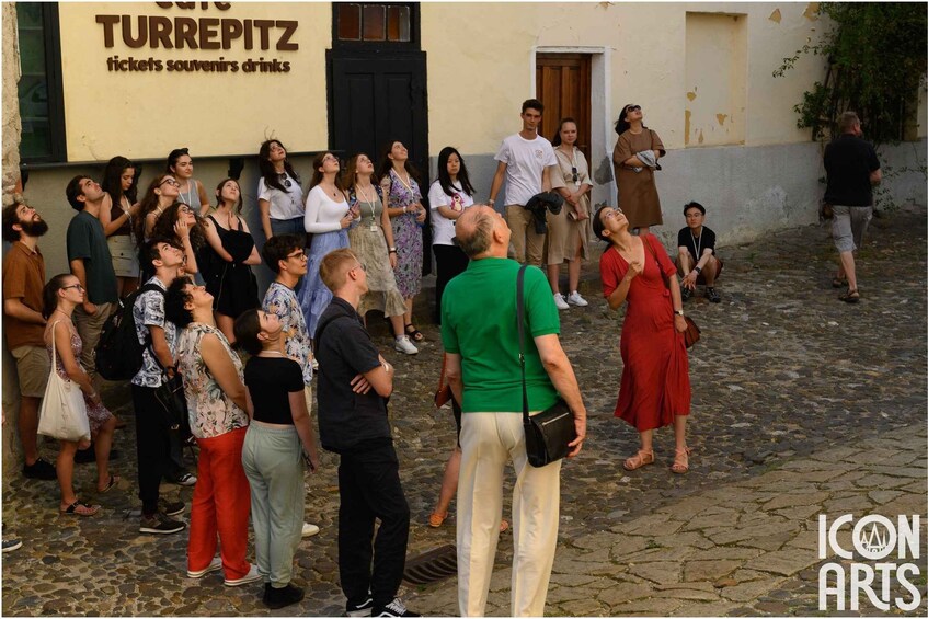 A group of people standing in front of a building with a sign that reads "Turrepitz tickets souvenirs drinks". 1