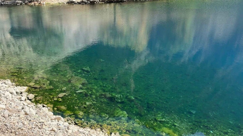 Un lac aux eaux claires, où l’on peut voir des rochers et une plage de galets. 3