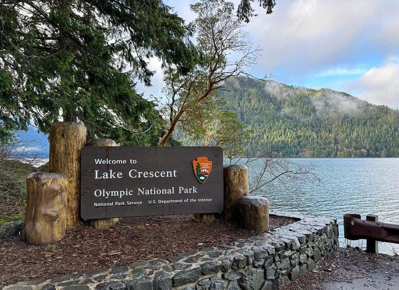 A welcome sign at Lake Crescent Olympic National Park with a lake and forested mountains in the background. 2