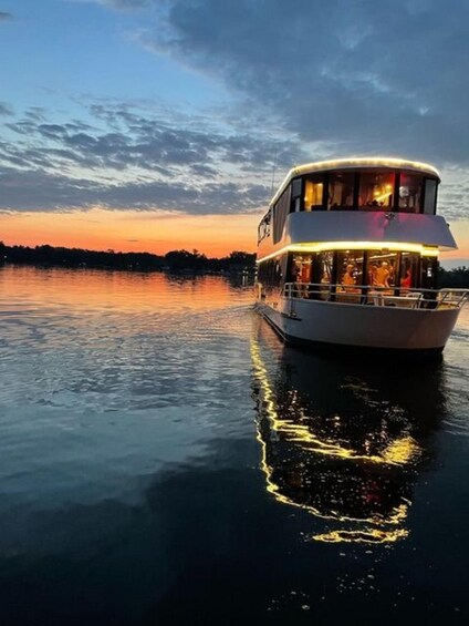A double-decked boat with lights on, reflecting on the water at sunset. 4