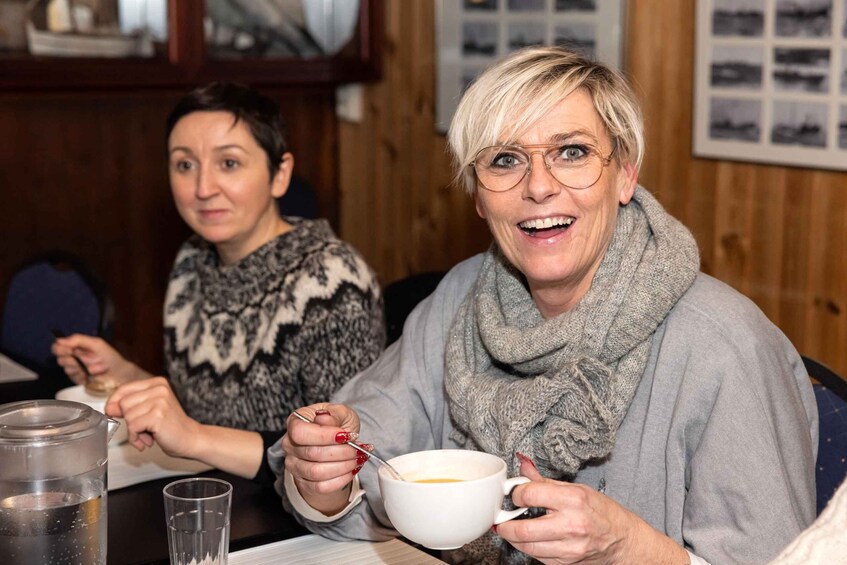 Two people sitting at a table with a white mug and a glass of water. 5
