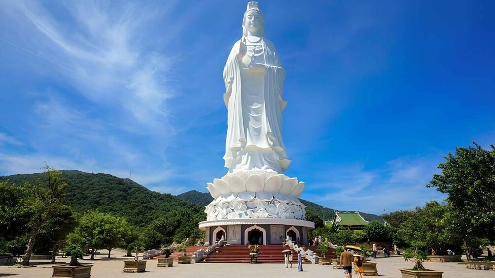 A large white statue with a lotus base, surrounded by a paved area with steps leading up to it. 5