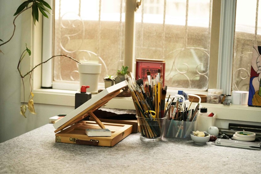 A workspace with an easel, art supplies, and a window with a view. 2
