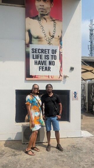 Two people standing in front of a wall with a motivational quote and a large poster. 5