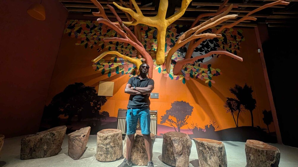 A man standing in front of a tree sculpture with branches and leaves. 4