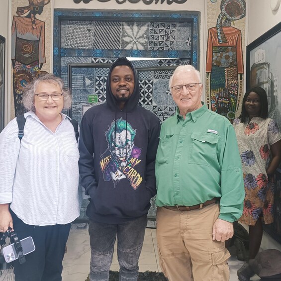 Four people standing in front of a wall with patterned tiles and artwork. 1
