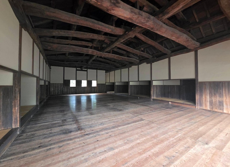 An interior with wooden beams, tatami mats, and a large open space. 5