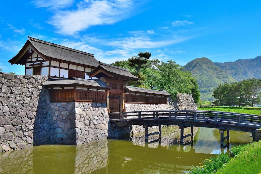 A traditional Japanese building with a stone wall and a wooden bridge over a pond. 1