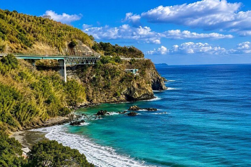 A coastal road with a bridge, cliffs, and turquoise sea. 5