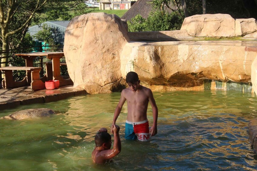 A man in a swimming pool with another person reaching out to him. 3