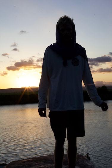 A person standing by a body of water during sunset. 2
