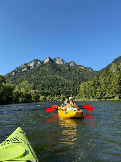 Two people kayaking on a river with mountains in the background. 4