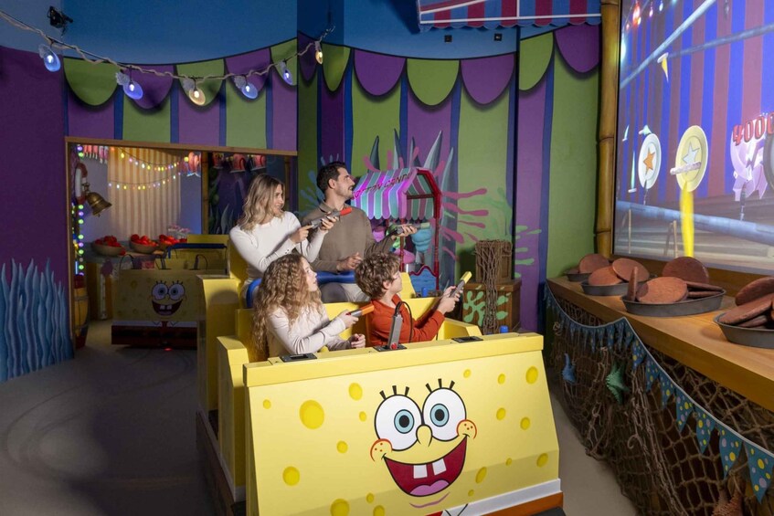 A themed play area with a yellow vehicle featuring SpongeBob SquarePants, a candy store, and a projection screen. 1