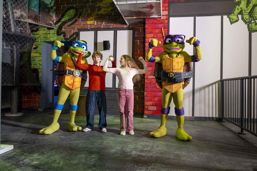 Four individuals in costumes, a brick wall, and a metal fence. 3