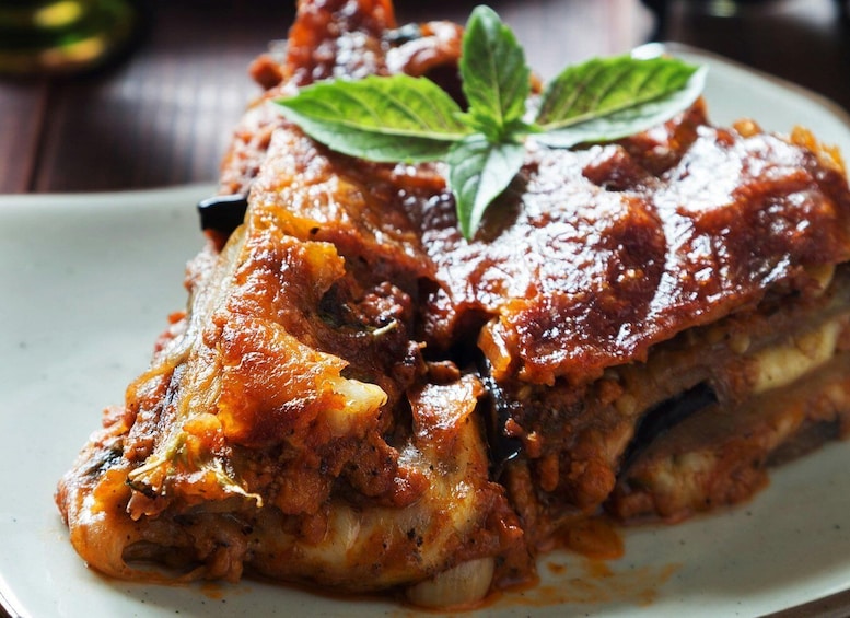 A plate of lasagna with a basil leaf garnish. 1