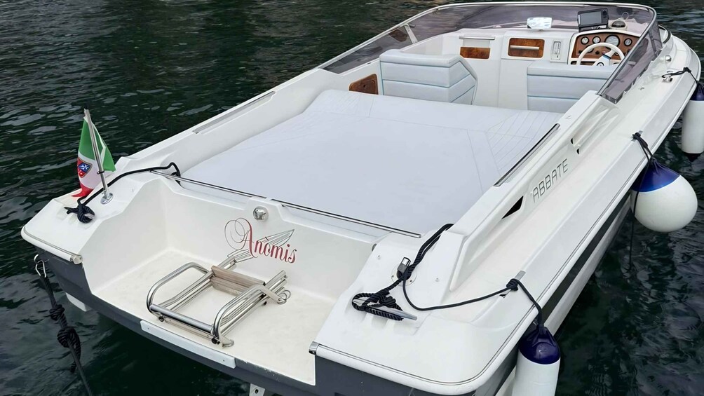 A white boat with 'Anomis' written on the bow, a steering wheel, and a small Italian flag. 2