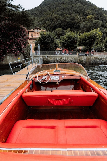 A red boat with a wooden interior, docked at a pier with a mountainous backdrop. 5