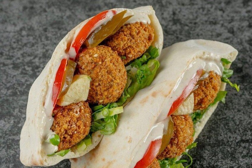 Un wrap de falafel con lechuga, tomates y salsa blanca. 2