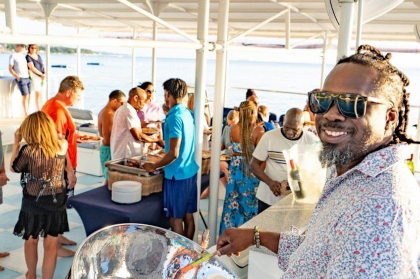 A group of people on a boat with a covered area, some standing and others seated, under a white canopy. 4