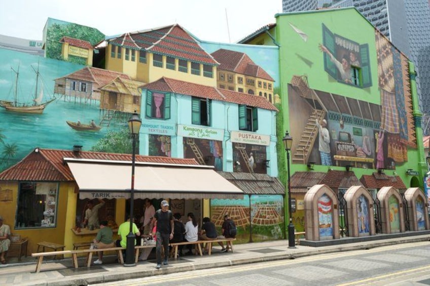 A street with colorful buildings, a bench, and a sign for 'Pustaka'. 5