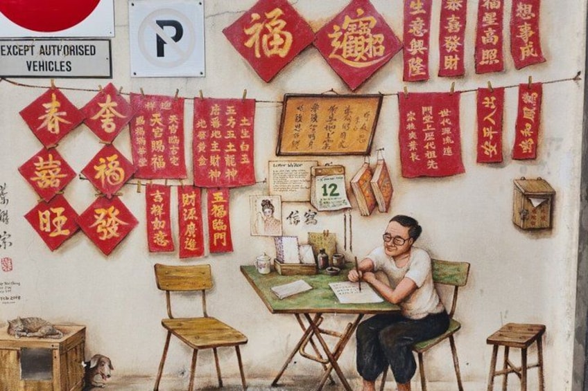A person sitting at a table with a chair, a wooden stool, and a cat on a small table. There are red banners with Chinese characters and a sign with the number 12. 2