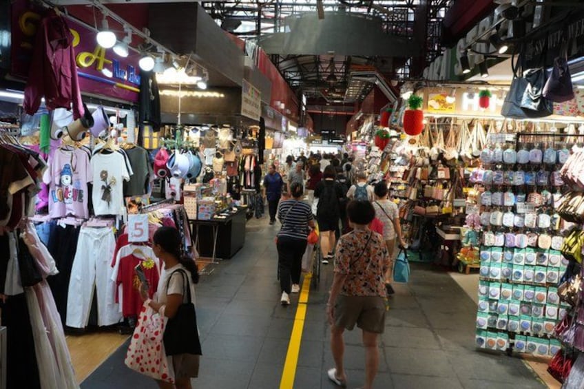 A busy indoor market with various stalls selling clothes and accessories. 4