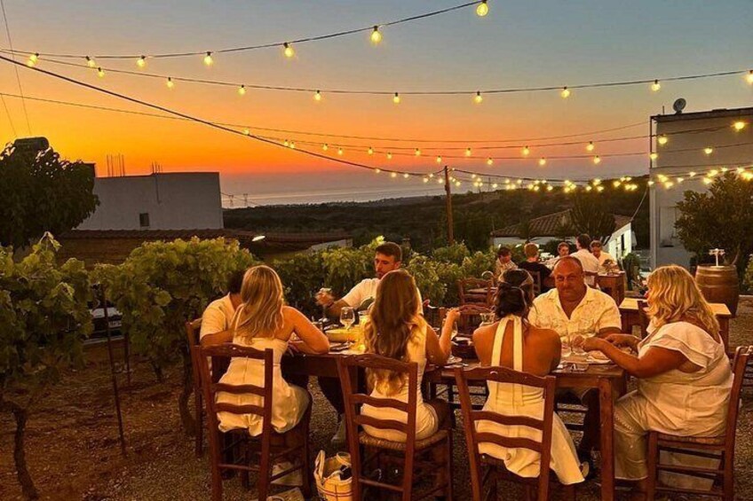 People dining outdoors at sunset with string lights overhead. 2