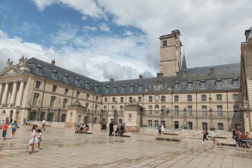 A historic courtyard with classical architecture, including a prominent building with columns and a clock tower. 3