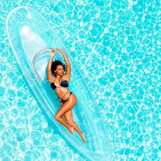 Una persona flota sobre un tubo inflable transparente en una piscina con agua azul. 2