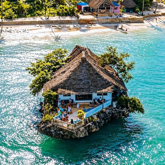 Ein Häuschen mit Strohdach auf einer kleinen Insel, umgeben von klarem, blauem Wasser. 5