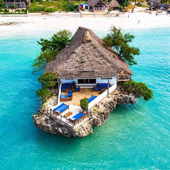 Ein strohgedecktes Bungalow auf einer kleinen Insel, umgeben von türkisblauem Wasser. 4