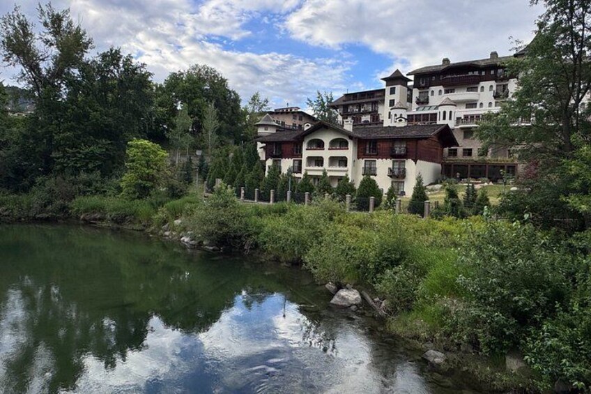 A river with a reflection of buildings, surrounded by greenery and trees. 2