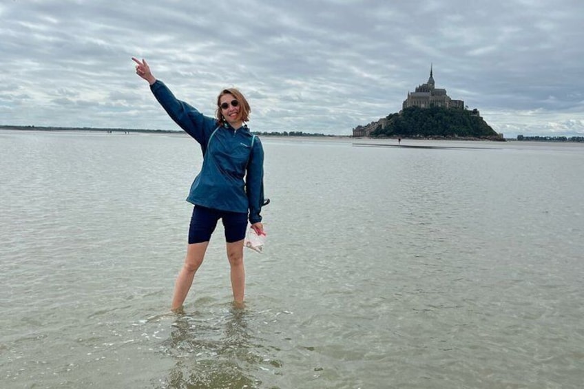 A person standing in shallow water with a castle on a distant island. 4