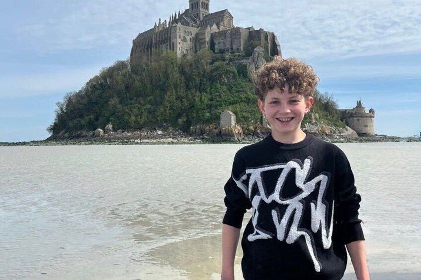 A person standing in shallow water with a historic castle and fortification in the background. 3
