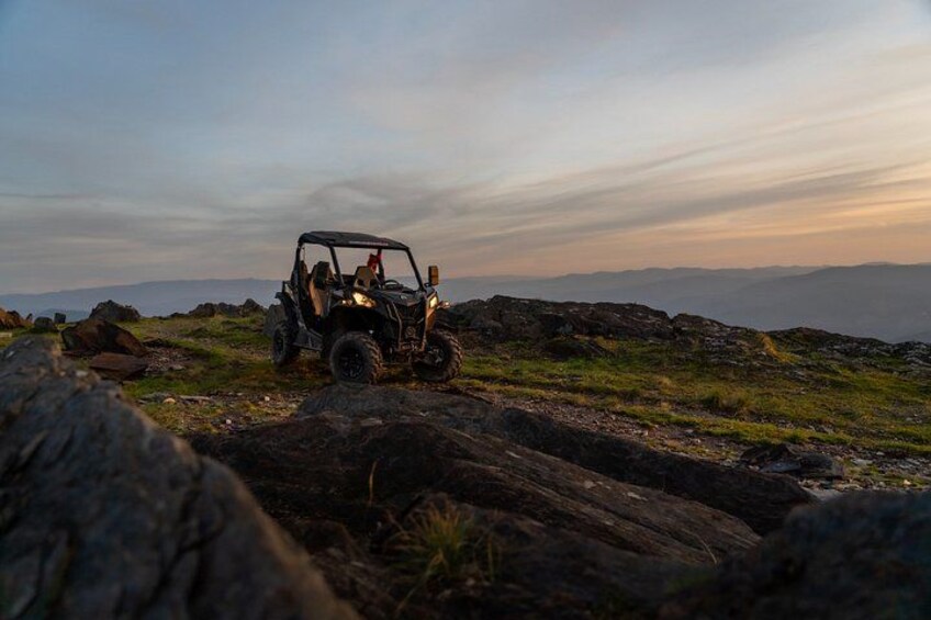 A vehicle on rocky terrain with a mountainous landscape in the background. 1