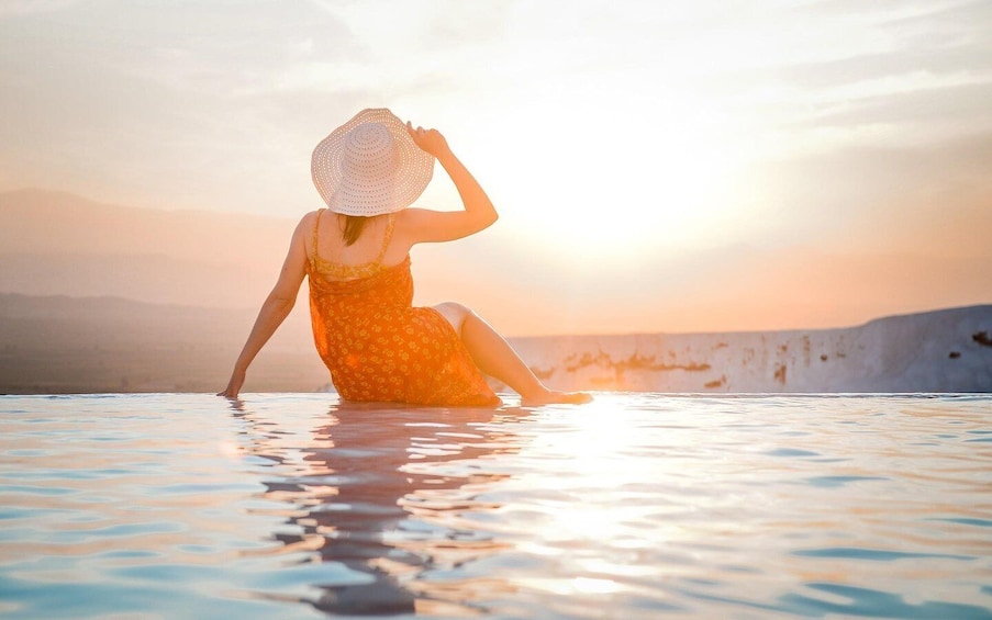 A person sitting in a pool with a sunset in the background. 5