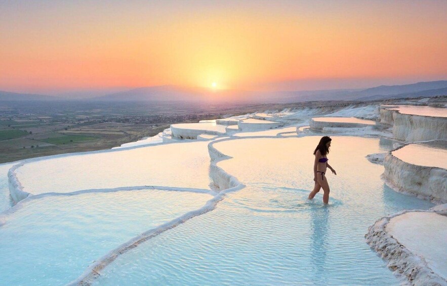 A person walking in a terraced pool at sunset. 4