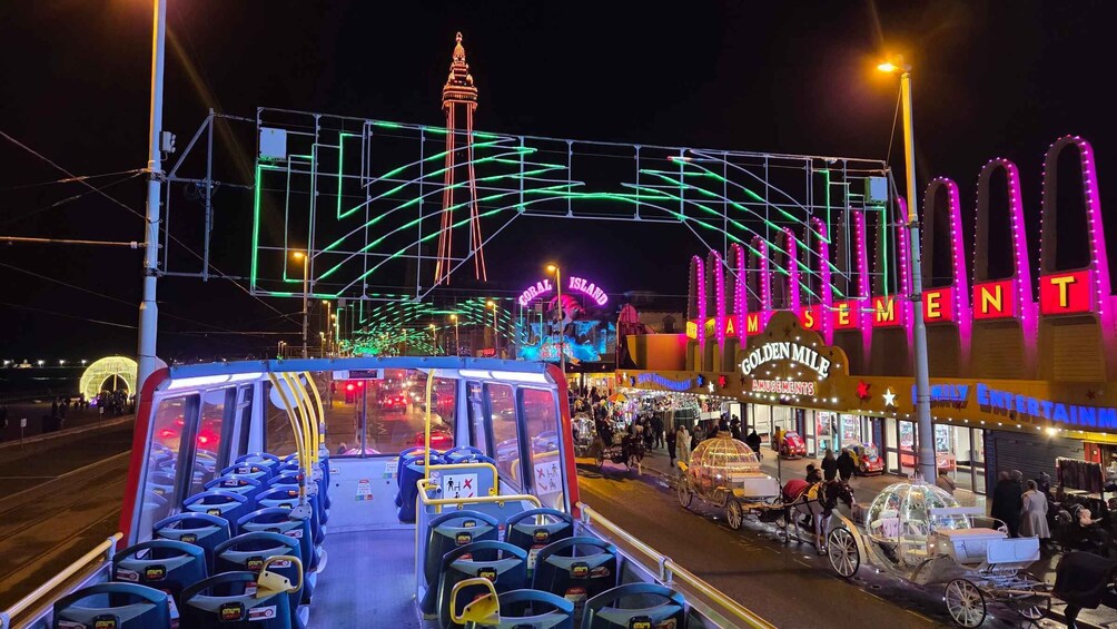 A brightly lit street with a bus, a carousel, and neon signs. 2