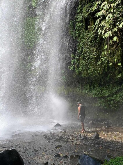 A waterfall with a person standing at the base. 1