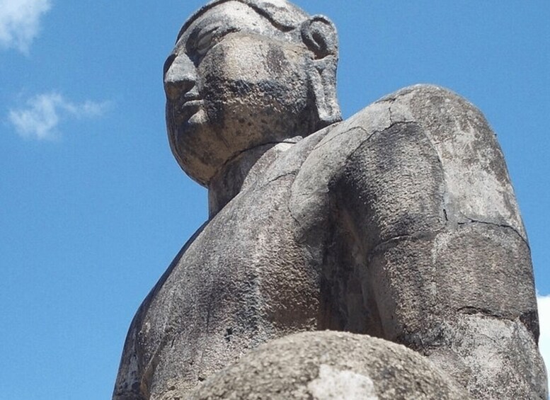 A large stone statue with a smooth surface and a clear sky in the background. 3