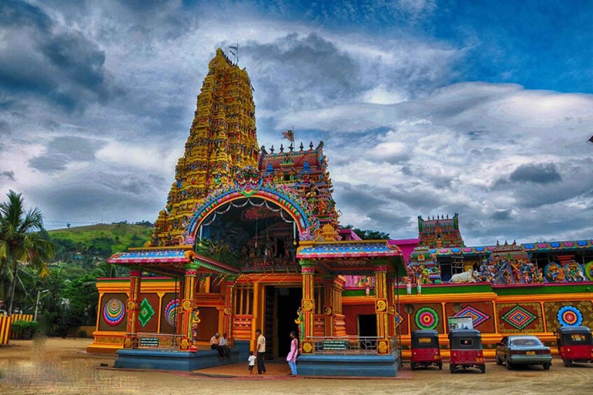 A colorful temple with a large spire, surrounded by lush greenery and a cloudy sky. 3