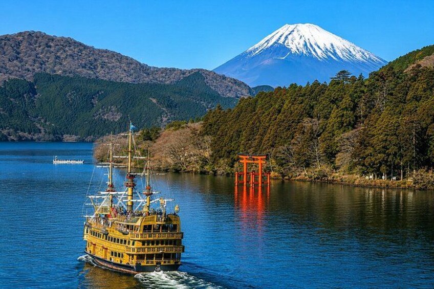 A yellow boat on a lake with a red torii gate and a snow-capped mountain in the background. 4