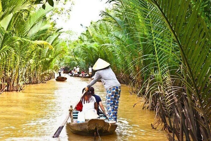 A person in a boat navigating a narrow waterway surrounded by dense tropical vegetation. 3